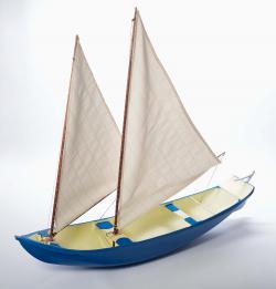 Embarcação provida de proa saliente; casco azul; dois mastros e duas velas latinas triangulares; estabilizador de bordo (bolina) em azul e branco; leme-de-cana em azul e branco.